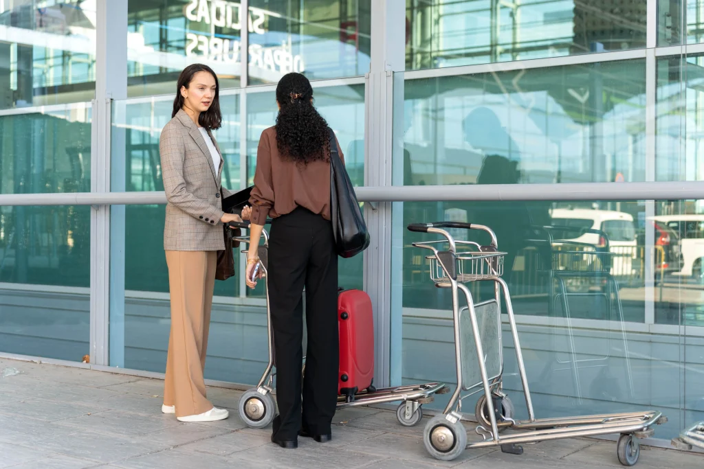 two-businesswomen-using-a-trolley-to-transport-lug-2025-03-10-16-02-59-utc-min